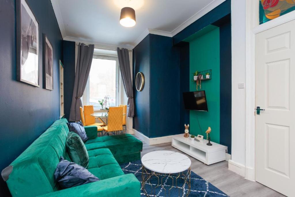 a living room with a green couch and blue walls at Boutique and Beautiful Edinburgh Abode in Edinburgh