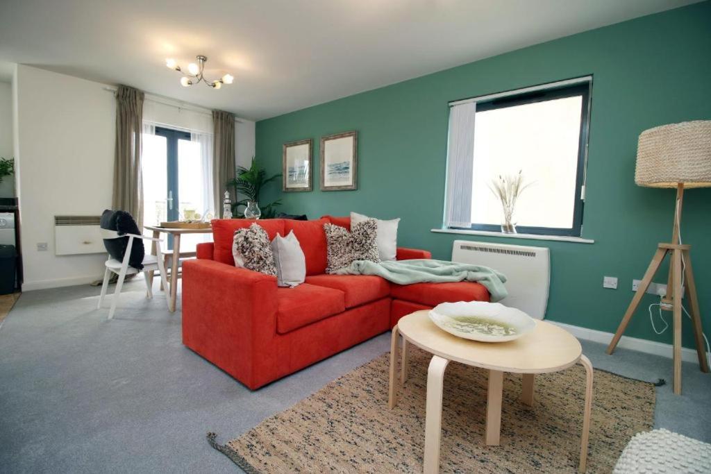 a living room with a red couch and a table at Observatory 2 bedroom apartment overlooking Beach in Swansea