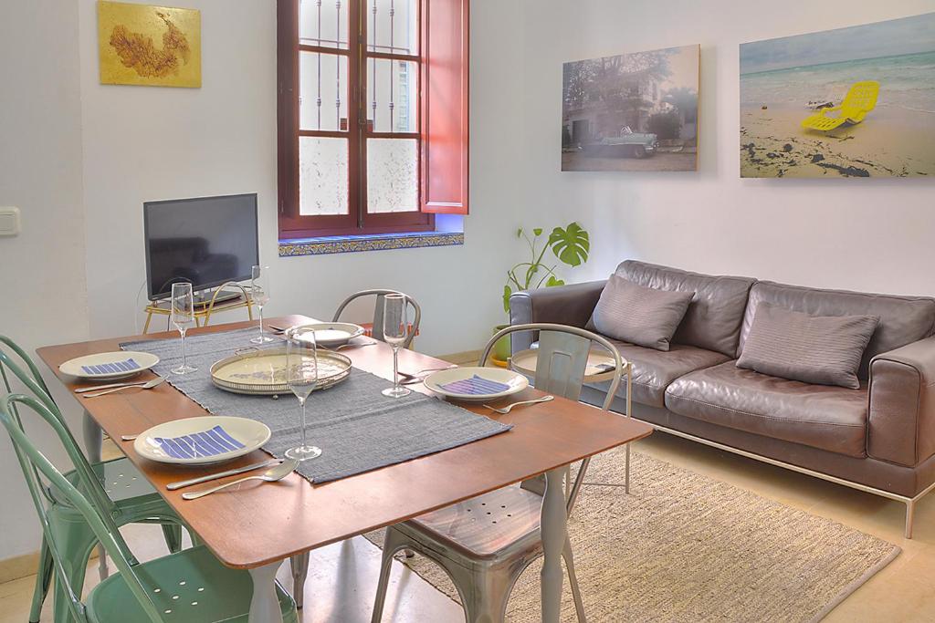 un soggiorno con tavolo e divano di Apartamento Torre de la Plata a Siviglia
