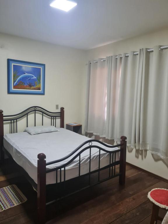 um quarto com uma cama e uma janela com cortinas em Aluguel de quarto em Torres