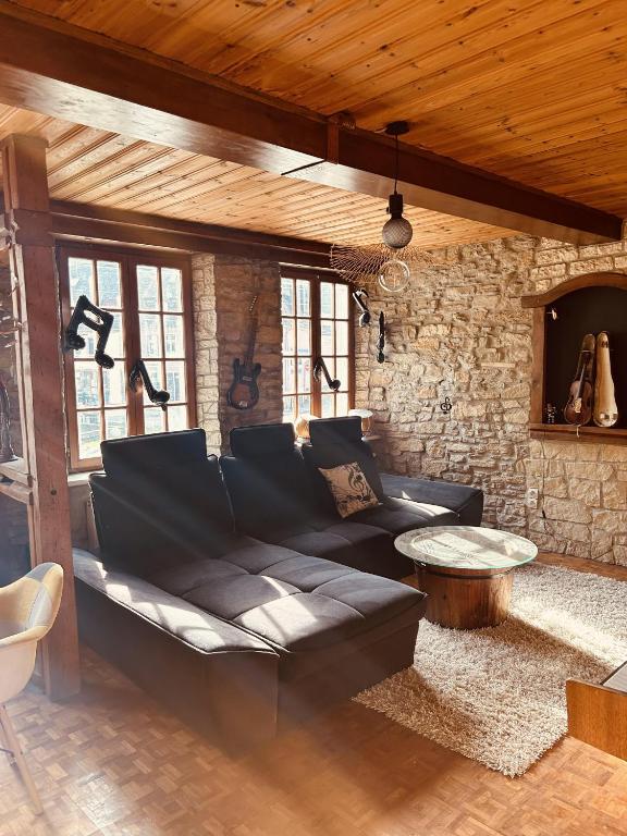 a living room with a black couch and a stone wall at LA MARIEFACTURE - Comme Si comme Fa in Sarreguemines