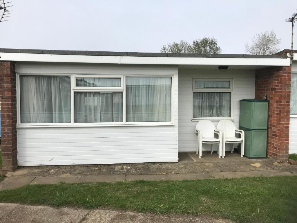a white house with two chairs and a refrigerator at Captivating 2-Bed Chalet in Great Yarmouth in Great Yarmouth