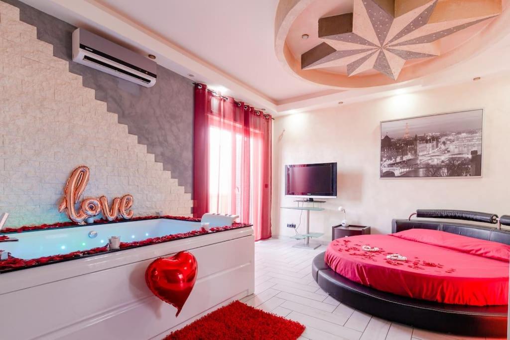 - une chambre avec un lit rouge et une baignoire dans l'établissement SuiteHouse - Jacuzzi & Comfort, à San Giorgio a Cremano