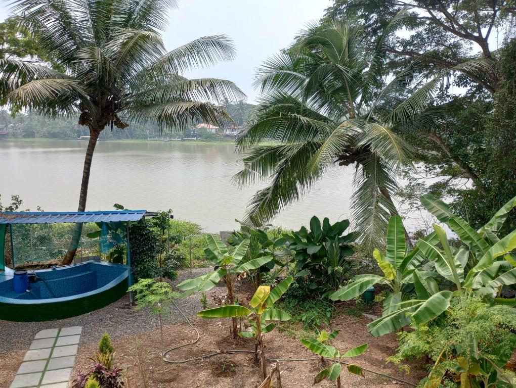 a blue boat on the shore of a river with palm trees at Waterfront Family Homestay ( Jameela Manzil). in Murinjupuzha