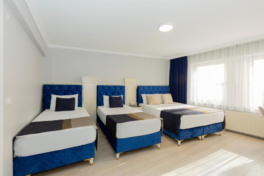 a room with three beds and blue chairs at Sirkeci Grand Family Hotel & SPA in Istanbul