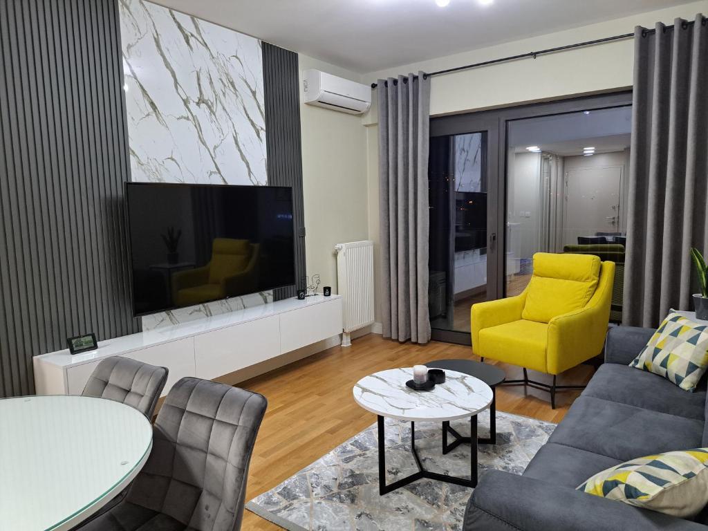 ein Wohnzimmer mit einem TV und einem gelben Stuhl in der Unterkunft Divine 69 Luxury Apartment, Skopje City - Center, Diamond Residences, free parking in Skopje