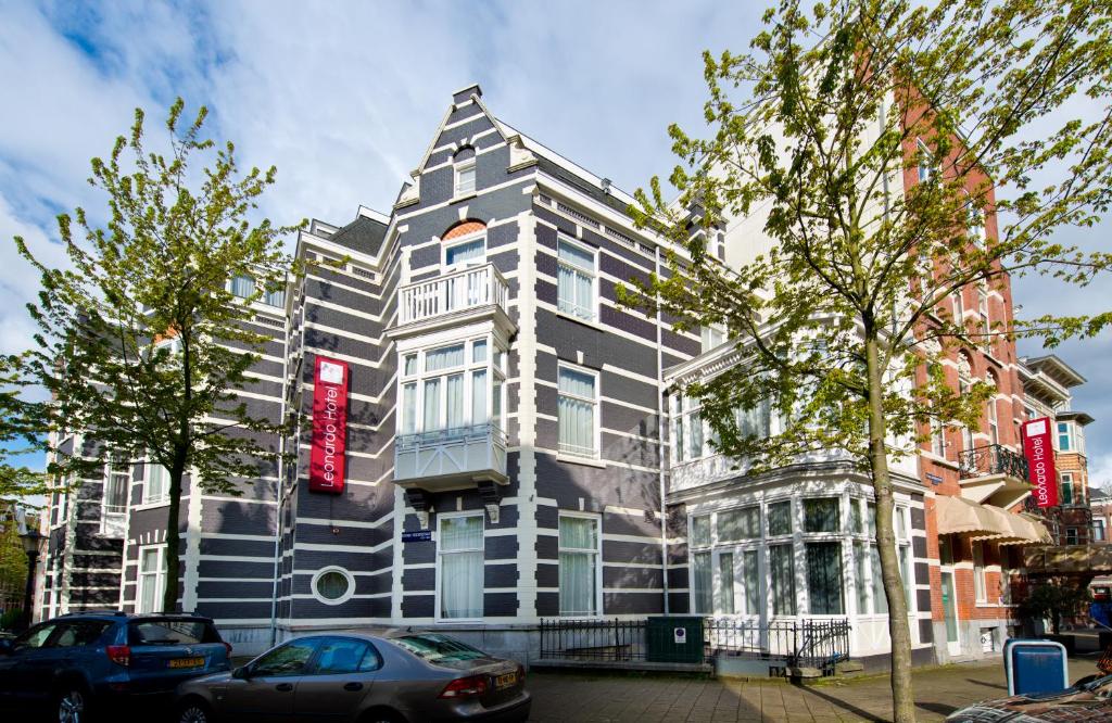 un edificio blanco y negro con un letrero rojo. en Leonardo Hotel Amsterdam City Center, en Ámsterdam