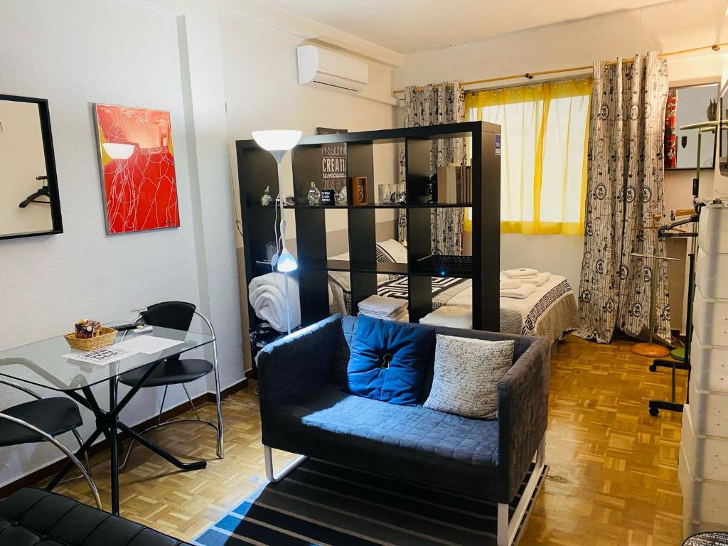uma sala de estar com uma cadeira azul e uma cama em Elegante Loft en Chueca em Madri
