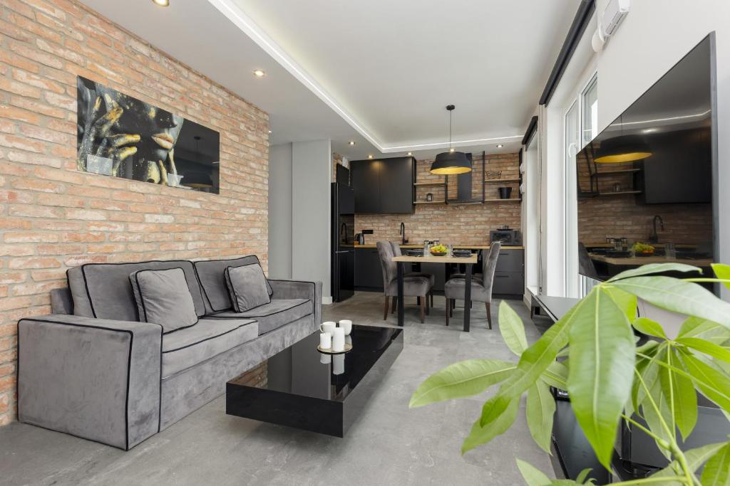 a living room with a couch and a brick wall at Milionowa Loft Apartment with Parking in Łódź by Noclegi Renters in Łódź
