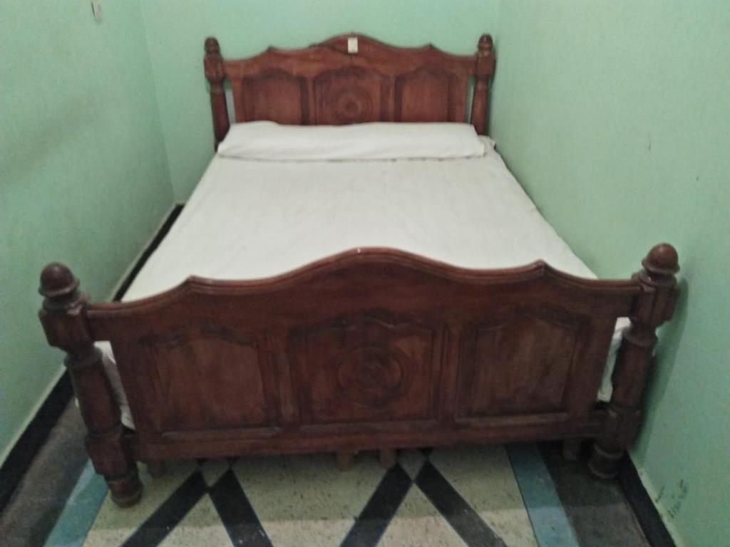 a wooden bed in a corner of a room at Dar joe Dassin in Zagora