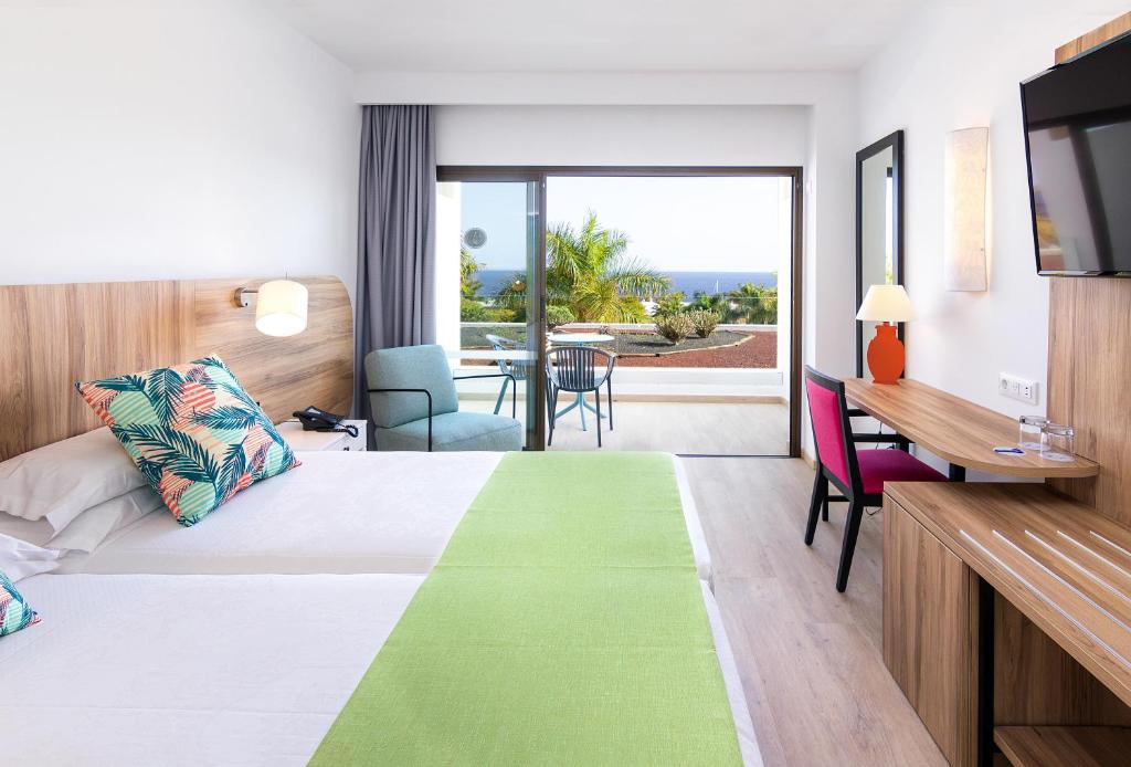 a hotel room with a bed and a desk and a television at Hotel Costa Calero Thalasso & Spa in Puerto Calero