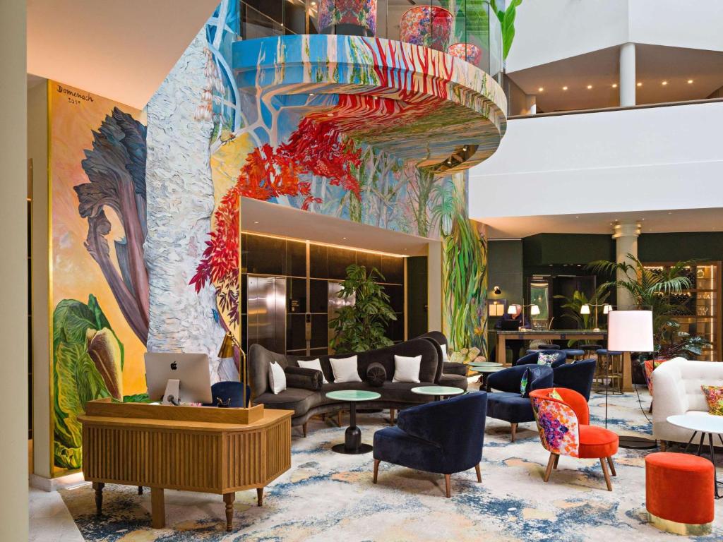 a lobby with couches and chairs and a mural at Sofitel Brussels Europe in Brussels