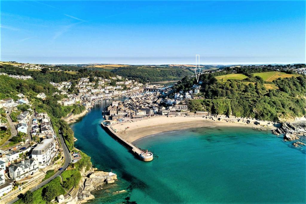 eine Luftansicht auf einen Strand mit einem Boot im Wasser in der Unterkunft The Captain's Lodge Looe in Looe