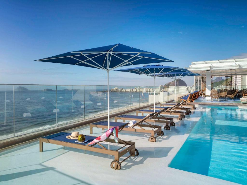 una piscina con panche e ombrelloni in cima a un edificio di Novotel Rio de Janeiro Leme a Rio de Janeiro