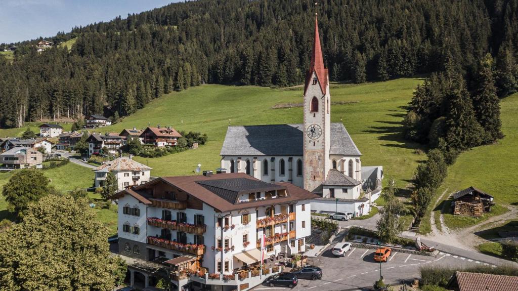 - une vue aérienne sur un bâtiment avec une église dans l'établissement Hotel Kirchenwirt, à Dobbiaco