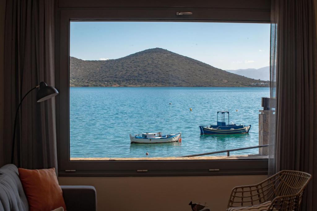 two boats in the water viewed from a window at Blue Cove Zen in Elounda