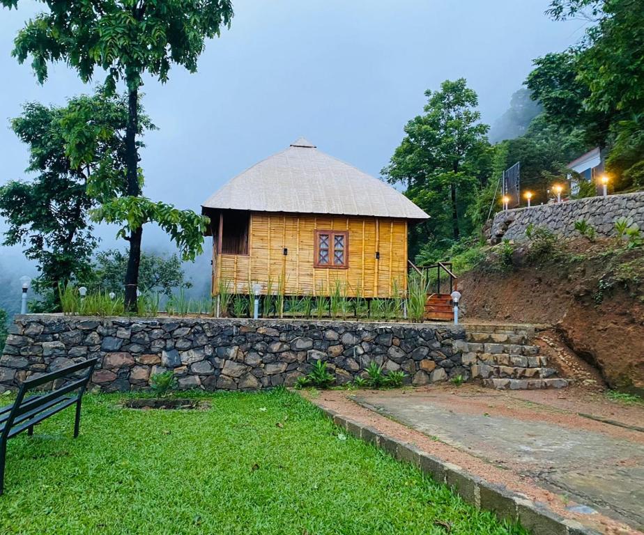a small hut with a stone wall and a bench at GAIRAH RESORT in Mundakāyam