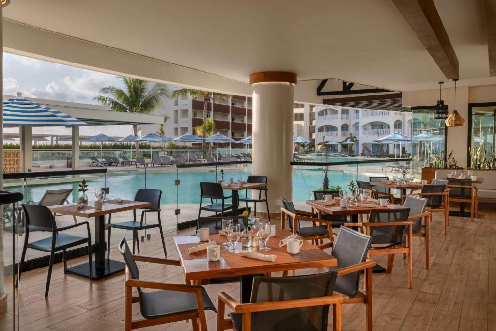 a restaurant with a pool and tables and chairs at Hilton Cancun Mar Caribe All-Inclusive Resort in Cancún