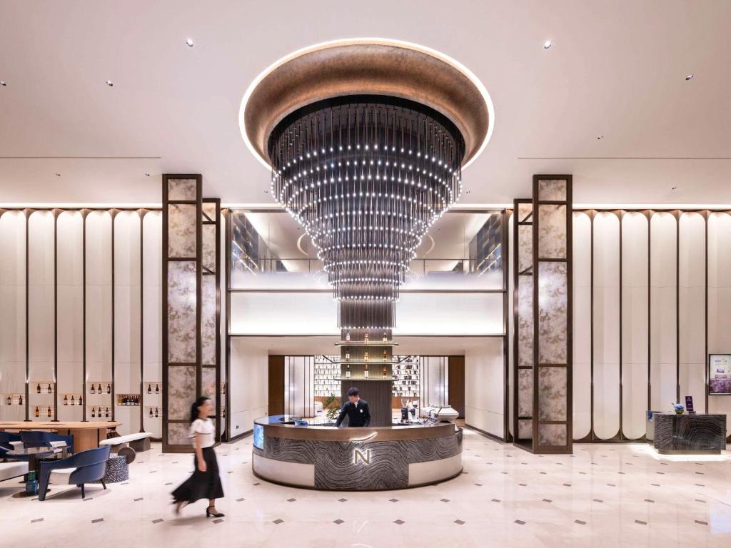 a woman walks through a lobby with a large ceiling at Novotel Shanghai JingAn in Shanghai