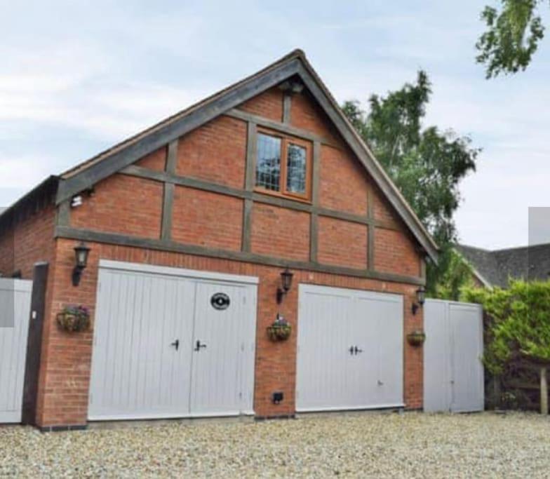 een bakstenen gebouw met twee witte garagedeuren bij Surrounded by fields just 3 miles from Stratford - upon Avon - Alveston Pastures Cottage in Stratford-upon-Avon