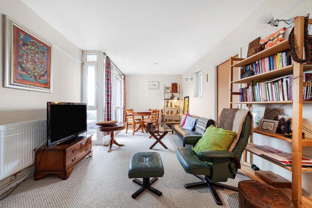 sala de estar con TV, sofá y sillas en Penthouse 1BR flat wbalcony & city view, Walworth, en Londres