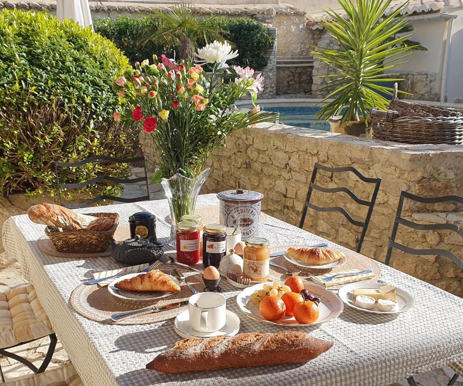 a table with plates of food and bread on it at Le Mas des Aires - Chambres d&#39;Hôtes - Blauzac -Uzès - Pont du Gard in Blauzac