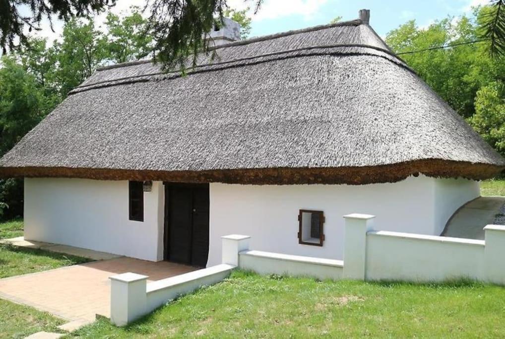 ein kleines weißes Gebäude mit Strohdach in der Unterkunft Romantic Cottage - Your Hide Away in Cserszegtomaj