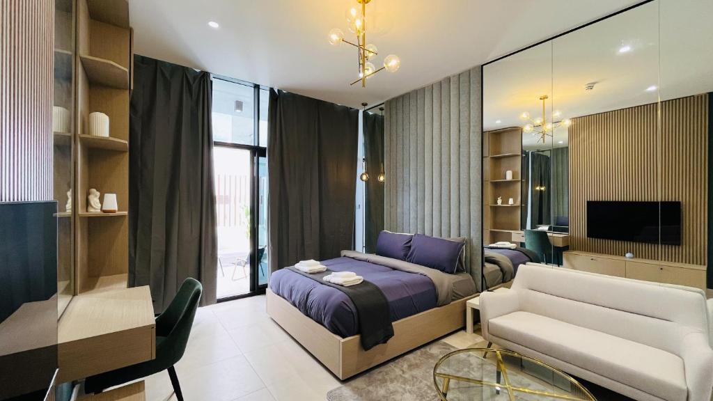 a bedroom with a bed and a couch and a tv at Modern Studio- 115 Westwood Al furjan in Dubai