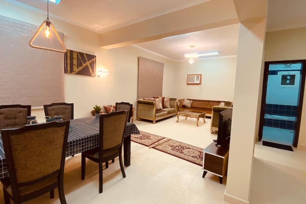 a dining room and living room with a table and chairs at Palm Villa in AlUla