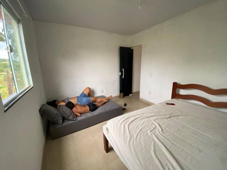 un uomo sdraiato su un divano in una stanza con un letto di Loft 1 Sítio do Barrigudinho a Saquarema