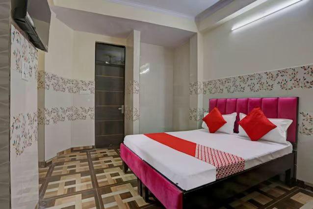 a bedroom with a large bed with red pillows at Hotel Thanks in New Delhi