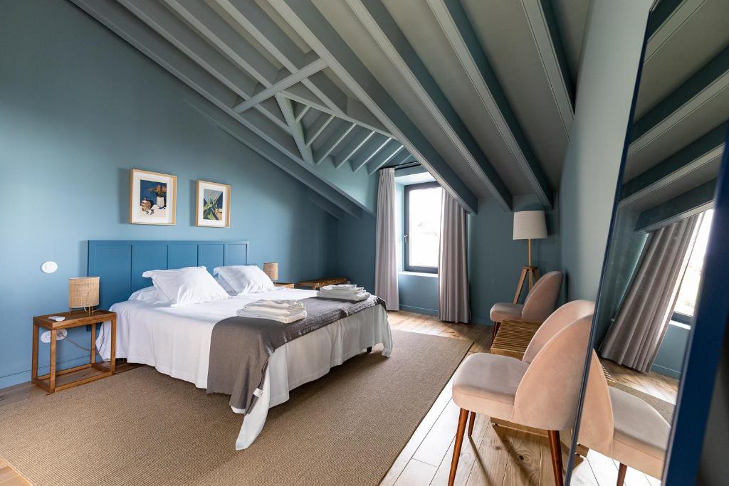 a blue bedroom with a bed and a chair at Guava Azores II in Ribeira das Tainhas