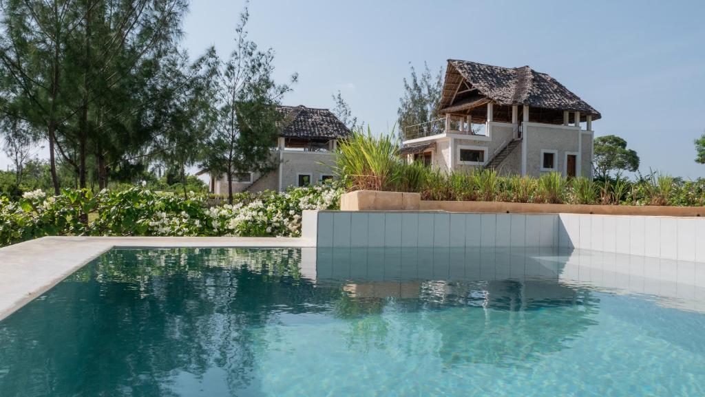 a house with a swimming pool in front of a house at Amani Villas Nature Retreat in Michamvi