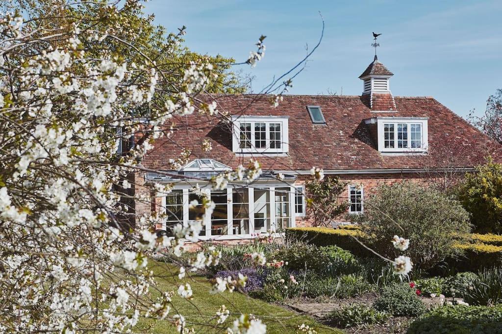 a red brick house with white windows and flowers at Filbert cottage, log fire and tennis court in Rolvenden