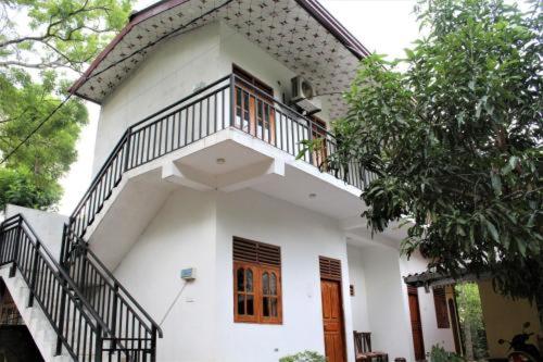 a white house with a staircase on top of it at ගයාන් ගෙස්ට් කතරගම in Kataragama