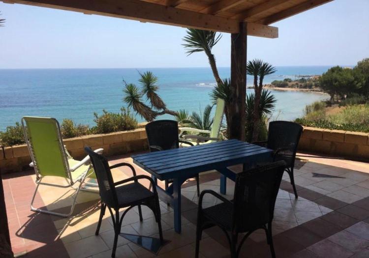 una mesa y sillas en un patio con vistas al océano en Repubblica delle pergole, en Realmonte