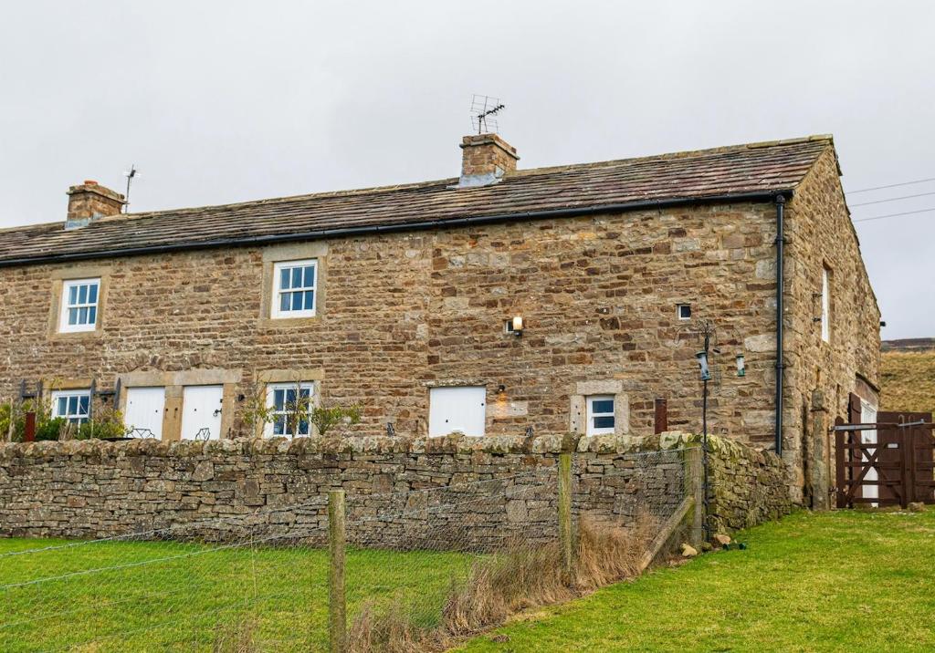 an old stone house with a stone wall at Sandpiper in Feetham