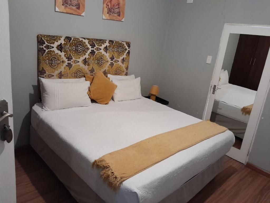 a bedroom with a bed with white sheets and orange pillows at Reitumetse GuestHouse in Maseru