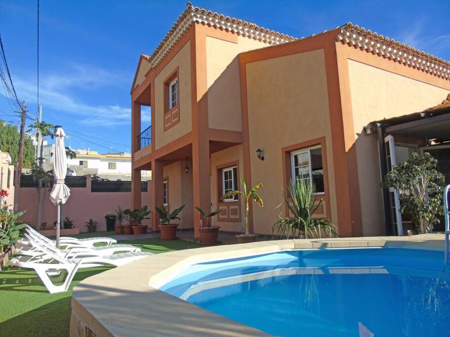 a villa with a swimming pool in front of a house at Luxurious villa with private pool - Villa Jardín in Santa Cruz de Tenerife