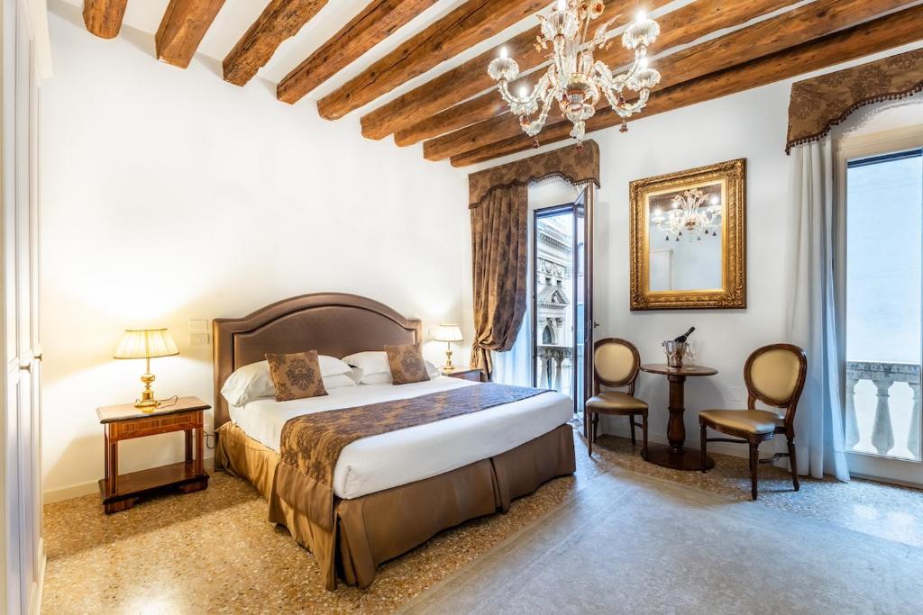 a bedroom with a large bed and a chandelier at San Teodoro Palace - Luxury Apartments in Venice