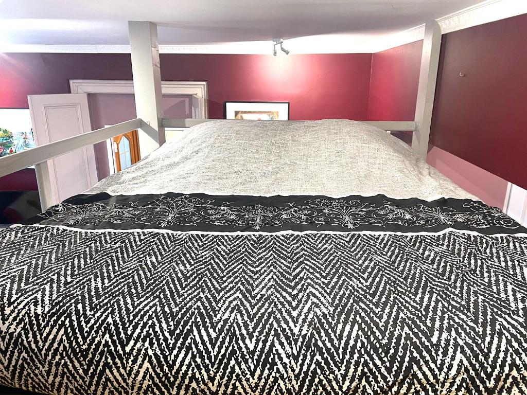 a bed with a black and white comforter in a bedroom at La Domus Lemaitre 1, plain-pied, Wifi , TV, parking, jardin 