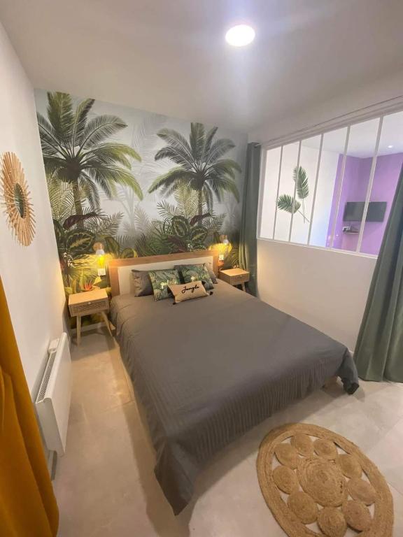 - une chambre avec un grand lit recouvert de palmiers dans l'établissement Escapades L'Isloises au cœur de L'Isle-sur-la-Sorgue., à LʼIsle-sur-la-Sorgue