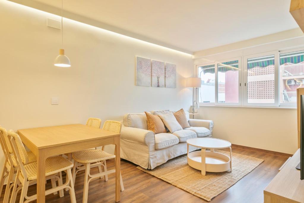 een woonkamer met een bank en een tafel bij Apartamento soleado y acogedor in Barcelona
