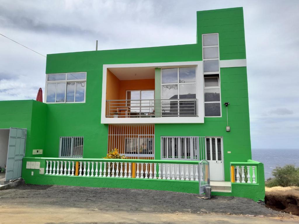 聖菲利佩的住宿－chez albino guest house，一座绿色房子,背景是大海