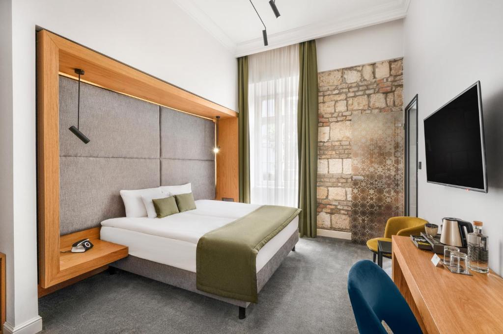 um quarto com uma cama, uma secretária e uma televisão em Monastery Boutique Hotel Budapest em Budapeste