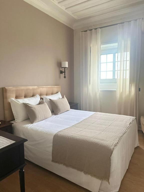 Un dormitorio con una gran cama blanca con ventana. en Hotel Joao Padeiro, en Aveiro