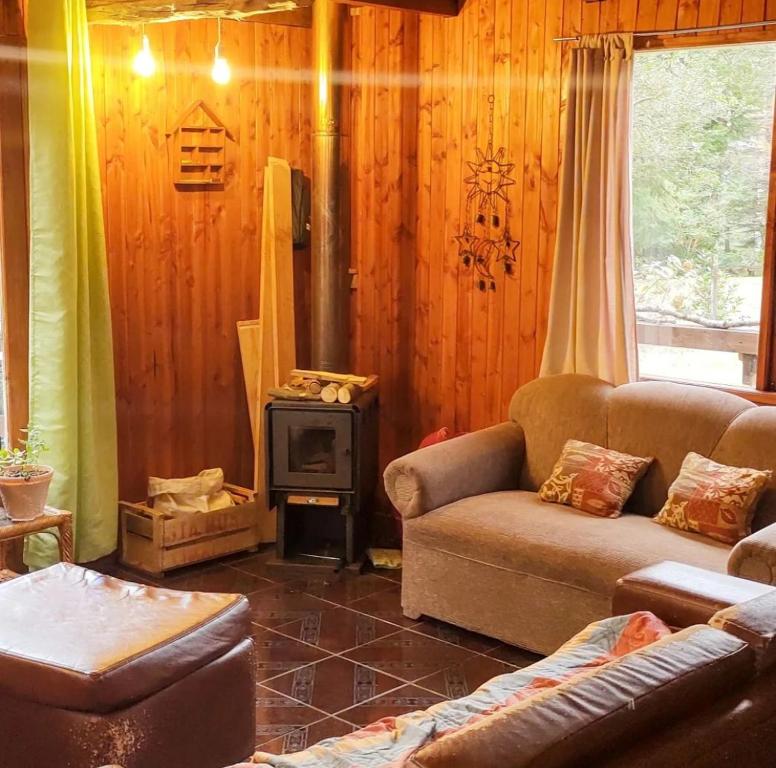 a living room with a couch and a stove at Cabaña Pachamama in Caburgua