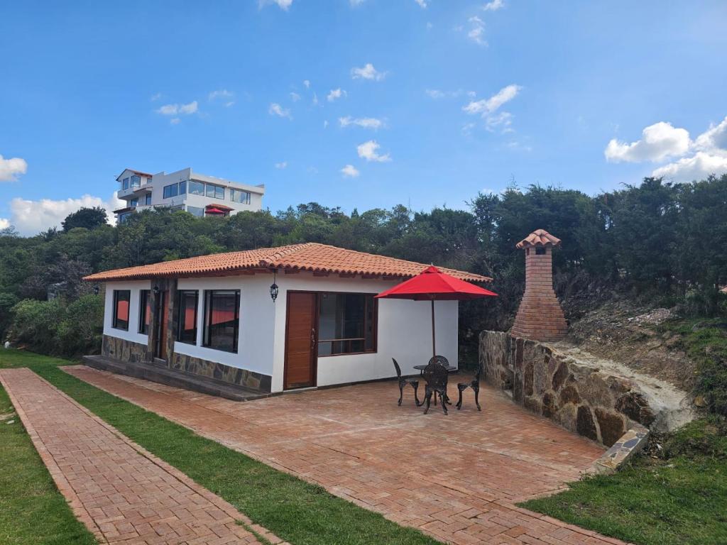 a small house with a red roof and a brick patio at Finca la Esperanza Casa para 7 Personas Ubaté Cundinamarca in Ubaté