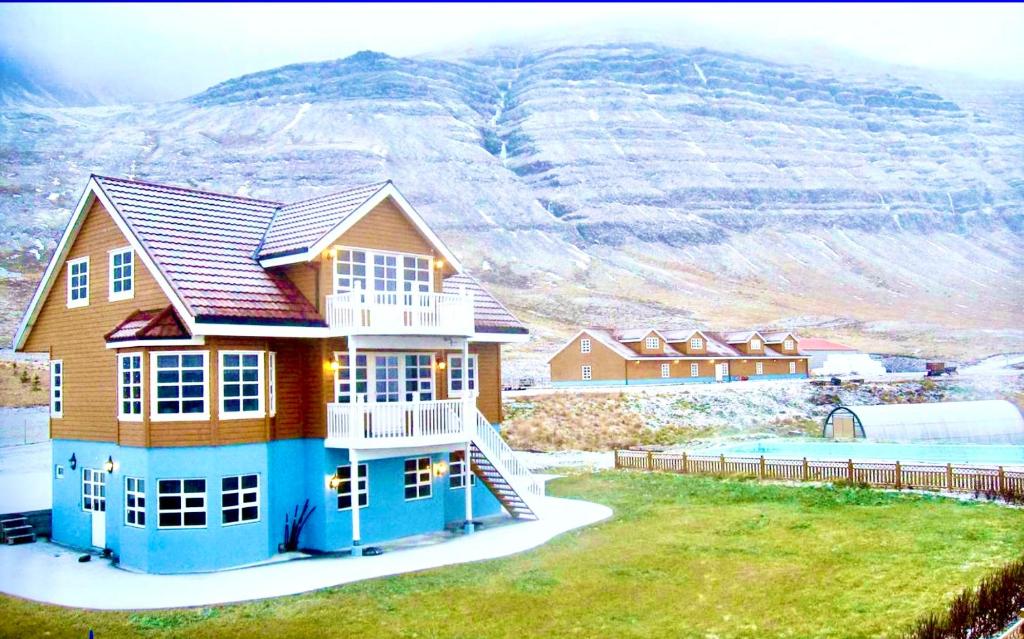 una casa en una colina con una montaña en el fondo en Guesthouse at Dynjandi Falls, en Bíldudalur