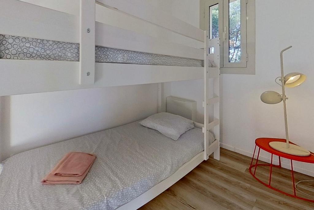 a bedroom with bunk beds with a table and a lamp at Résidences Sopramare in Algajola